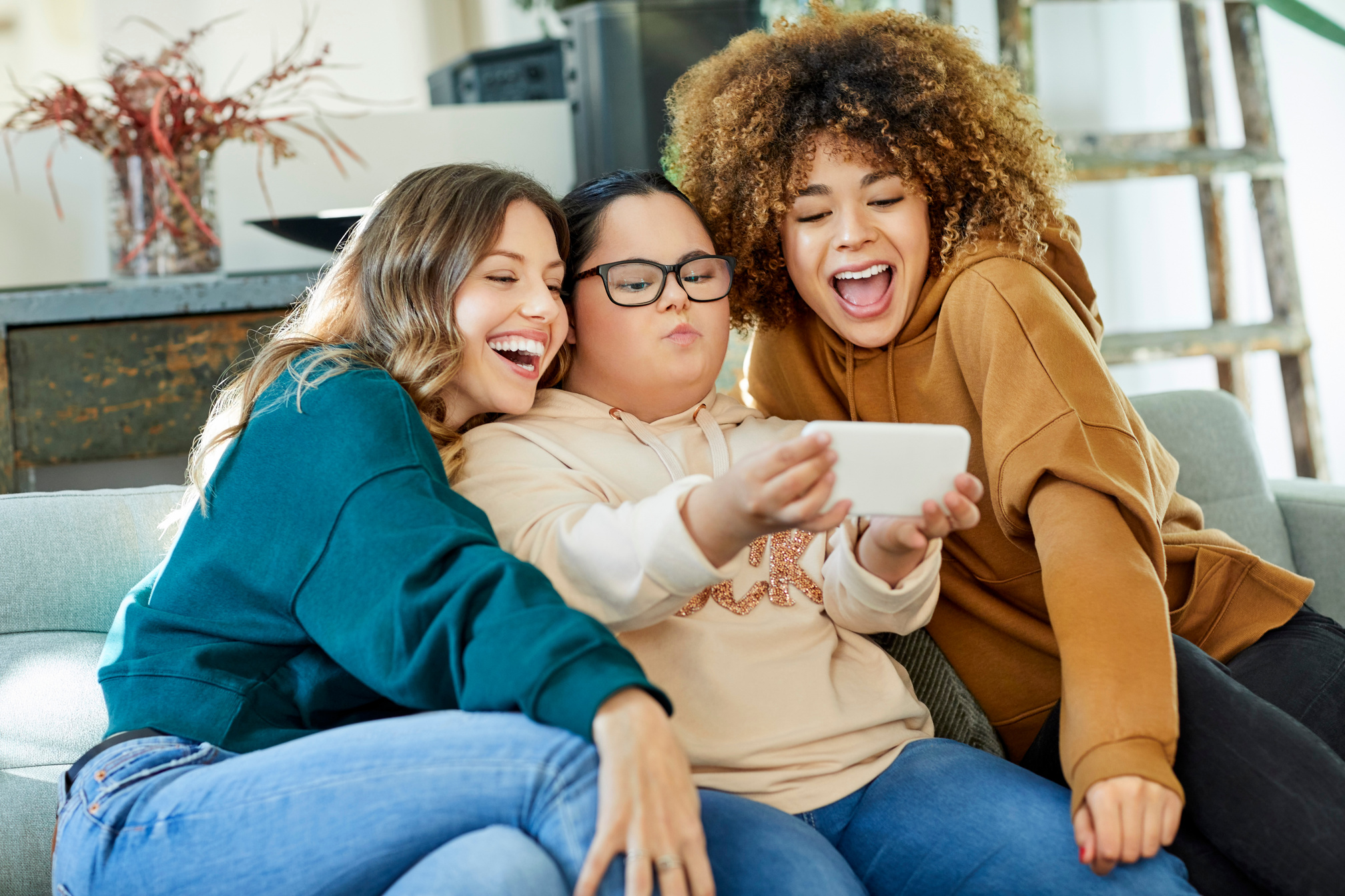 Disable woman taking selfie with friends on sofa